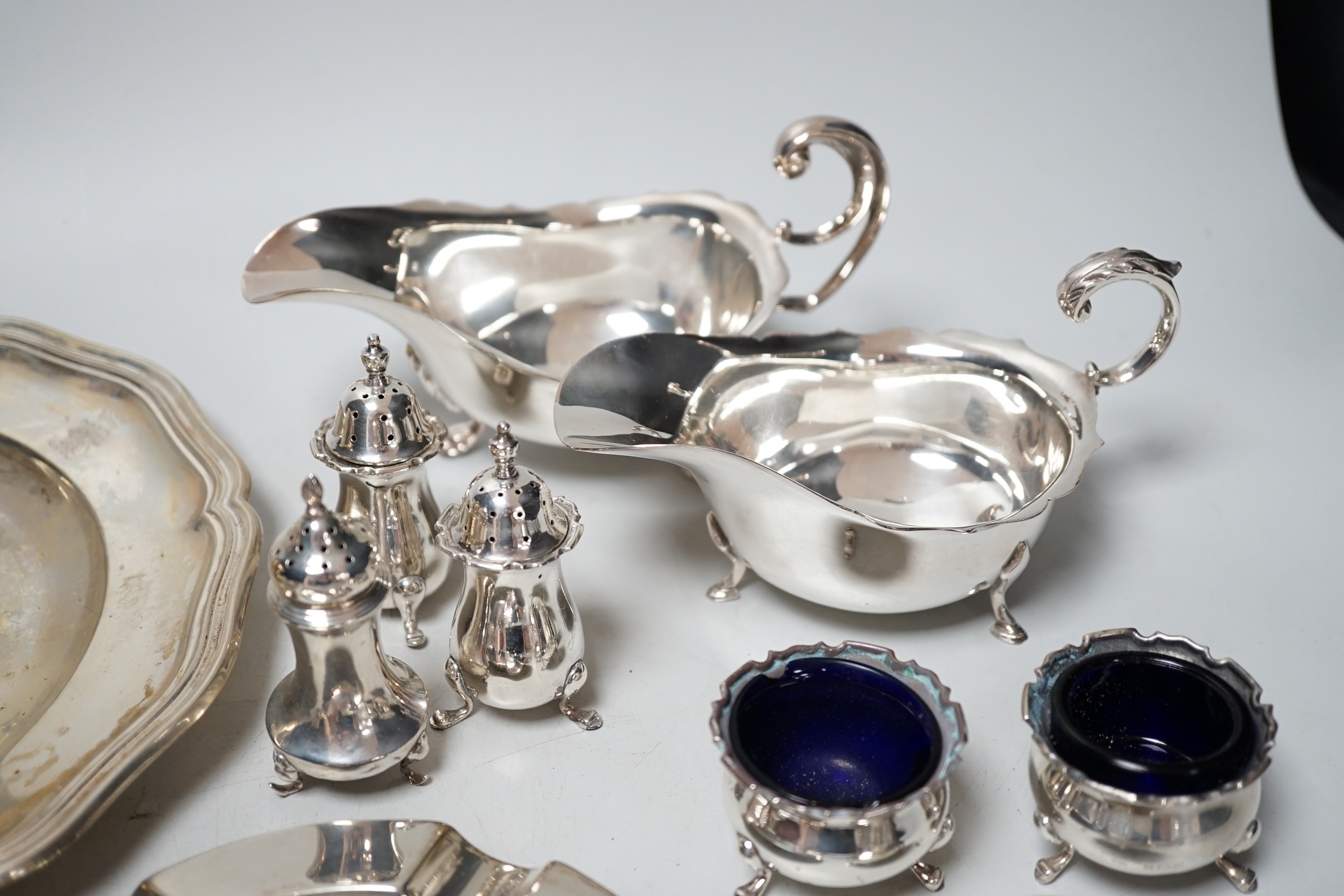 An 800 white metal plate, 24.8cm, a George V silver two handled bowl, a silver ashtray, six silver condiments, two 800 tots and minor plated ware, 24.1oz.